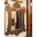 An early 20th century reproduction of a Georgian fretwork walnut and parcel gilt mirror surmounted