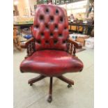 A reproduction office chair upholstered in a burgundy button back leather