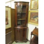 A reproduction mahogany serpentine fronted floor standing corner cupboard