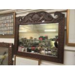 A carved oak wall mirror with a swan neck top with bird design