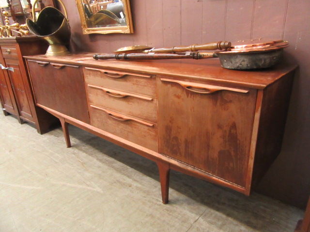 A mid-20th century design teak sideboard having a pair of cupboard doors with three drawers with