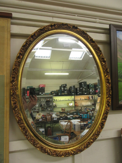 An ornate gilt framed oval bevel glass wall mirror
