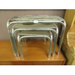 A nest of three chrome legged smoked glass topped occasional tables