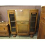 A mid-20th century oak bureau bookcase having a pull down flap to centre with drawer and cupboard