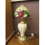 A gilt painted ceramic table lamp having a Tiffany style shade