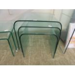 A nest of three bent glass occasional tables