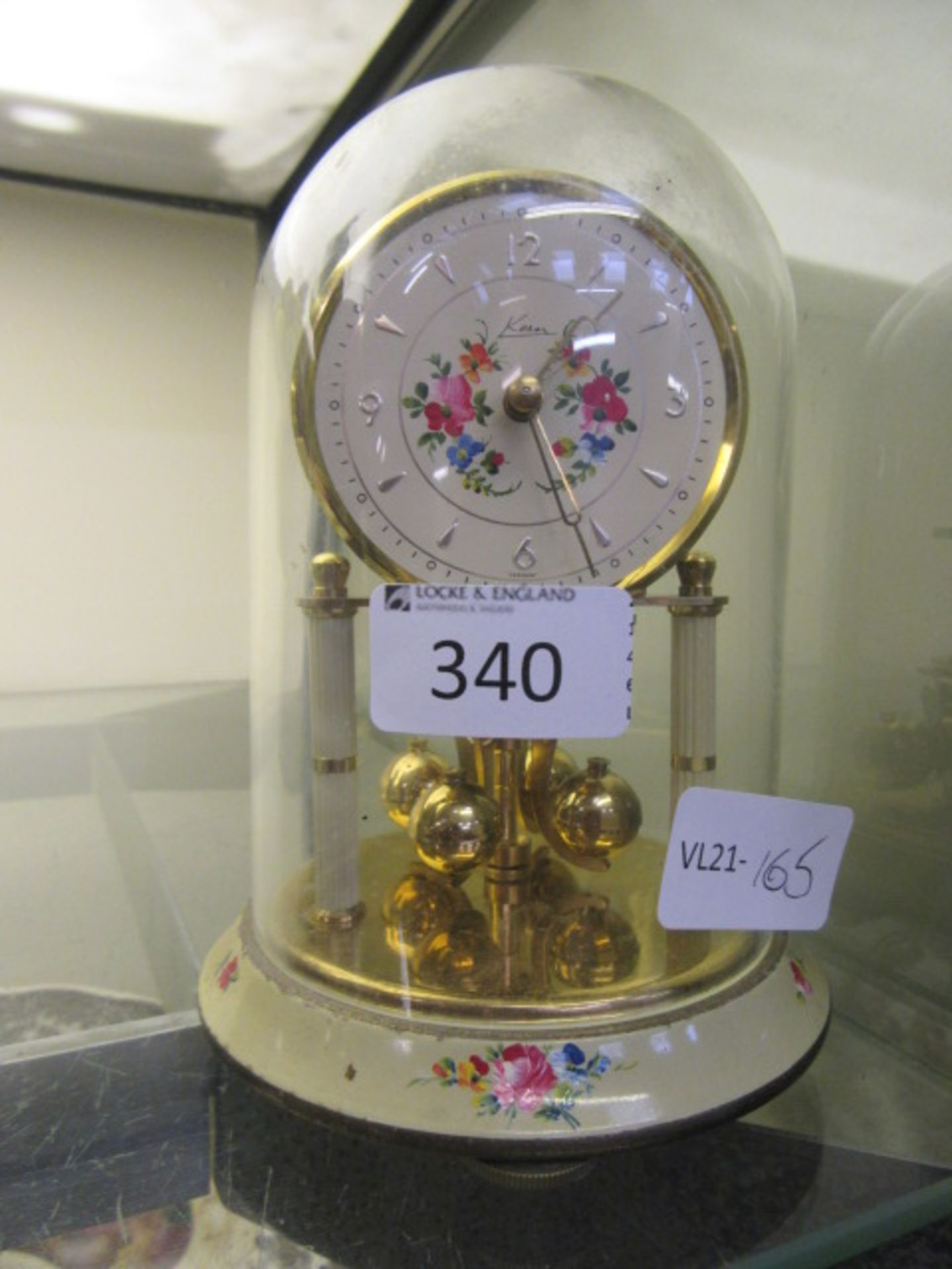 A brass and enamelled anniversary clock under dome