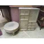 An embossed metal wooden cabinet with drawers and cupboard along with a matching stand