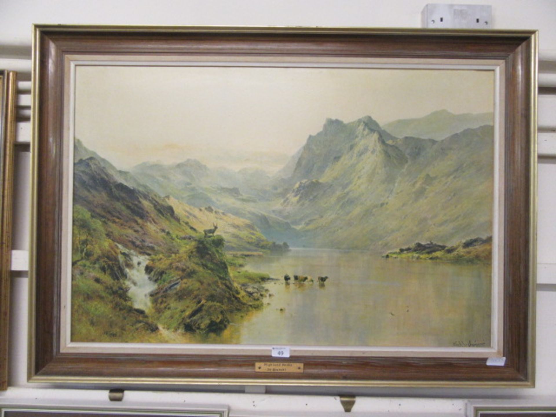 A framed oleograph of cattle in lake scene titled 'Highland Peaks' after De Brenski