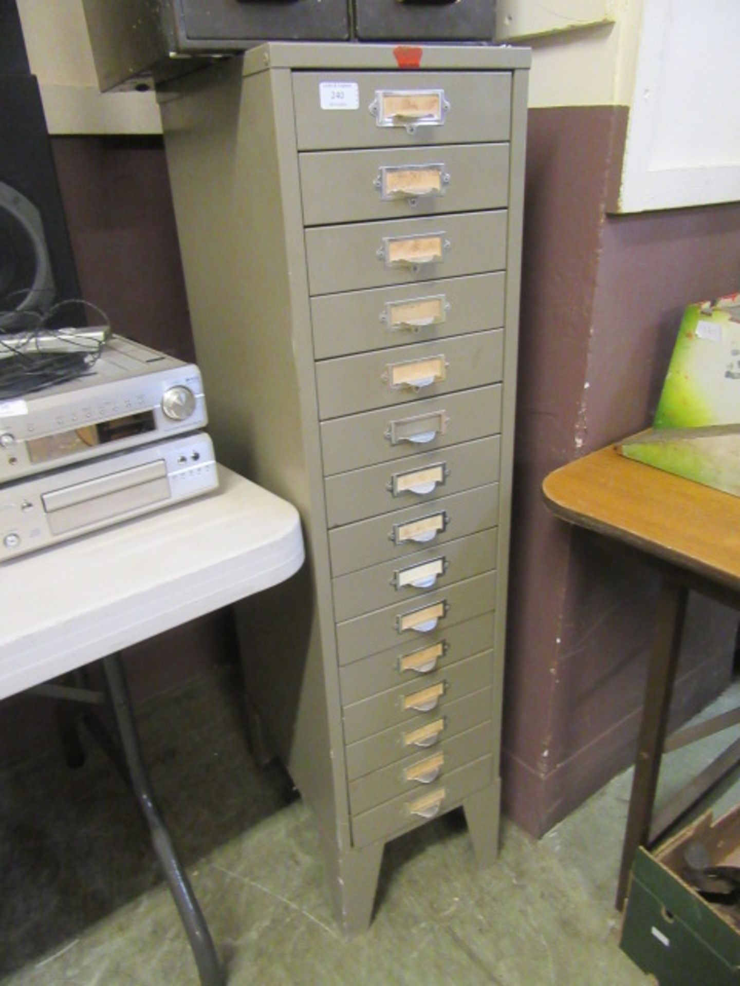 A grey metal fourteen drawer stationery cabinet