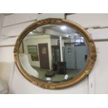 An ornate gilt framed oval bevel glass mirror