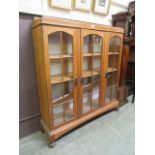 An early 20th century oak display cabinet having three glazed doors enclosing adjustable shelving