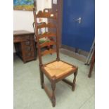 An early 20th century oak ladder back chair with rush seat