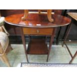 An Edwardian flame mahogany oval drop-leaf table with centre drawer and under tier