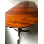 TRIPLE PILLAR DINING TABLE, Regency style mahogany with rounded ends raised upon triple pillar