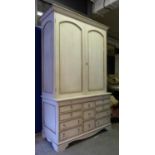 BOOKCASE, in a distressed finish with two panelled doors enclosing two further doors and swag,