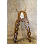 GUN RACK, with deer hooves and antler skull mounted on oak back, 128cm H x 63cm.