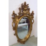 WALL MIRROR, Continental style gilt with scroll and flowerhead decoration and an oval bevelled