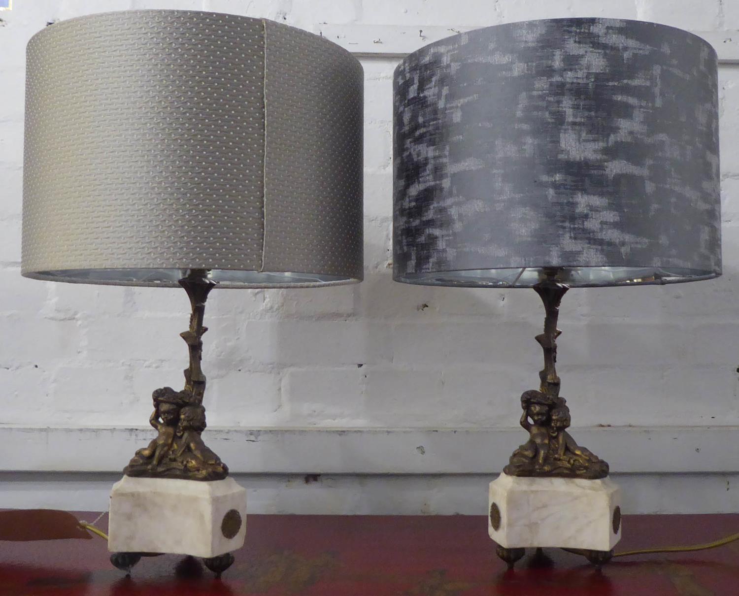 TABLE LAMPS, a pair, with gilt metal putti on triform marble bases, 52cm H including shades. (2)