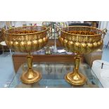 FLOOR STANDING URNS, on stands, a pair, gilt metal, 76cm H x 65cm Diam.