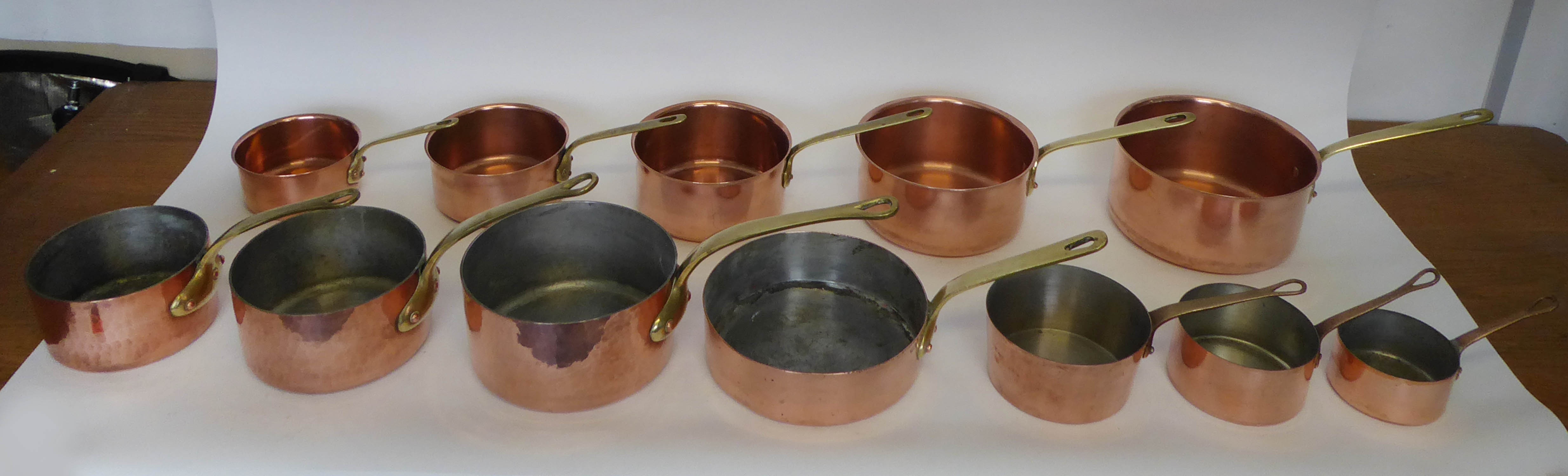 BATTERIE DE CUISINE, a set of five graduated copper pans, each with a brass handle, the largest 21cm