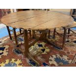 VENDAGE TABLE, 19th century French oak with a circular tilt top on trestle supports, 103cm diam x