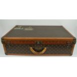 LOUIS VUITTON SUITCASE, early 20th century, classic monochromed with leather trim and brass locks,