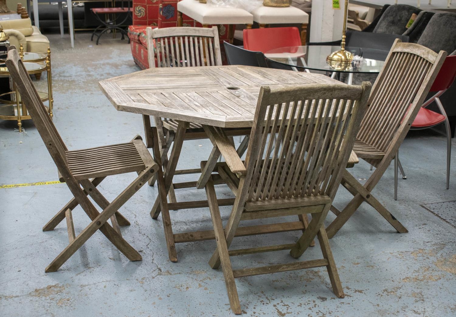 GARDEN TABLE, octagonal weathered teak on folding legs, 74cm H x 120cm W and a set of four folding