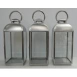 STORM LANTERNS, a set of three, polished metal and glass, 60cm H. (3)