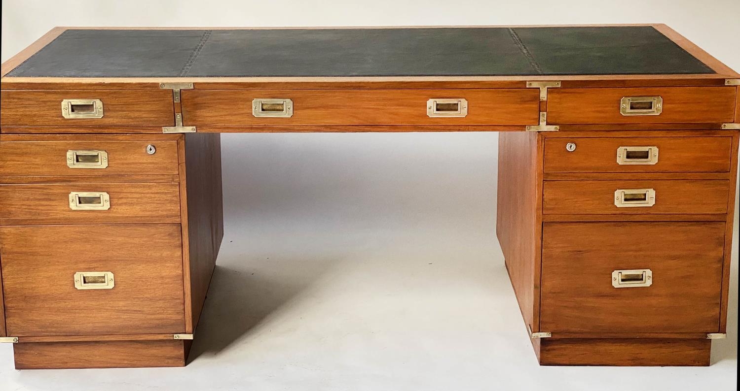 PEDESTAL DESK, campaign style faded teak and brass bound with nine drawers and tooled black