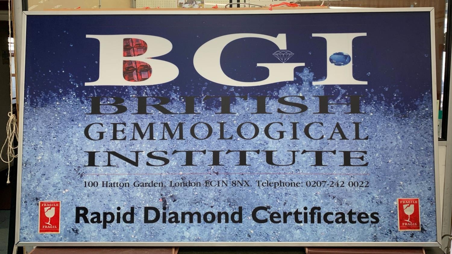 BGI ADVERTISING SIGN, 116cm H x 207cm W, back lit, encased in a metal frame.