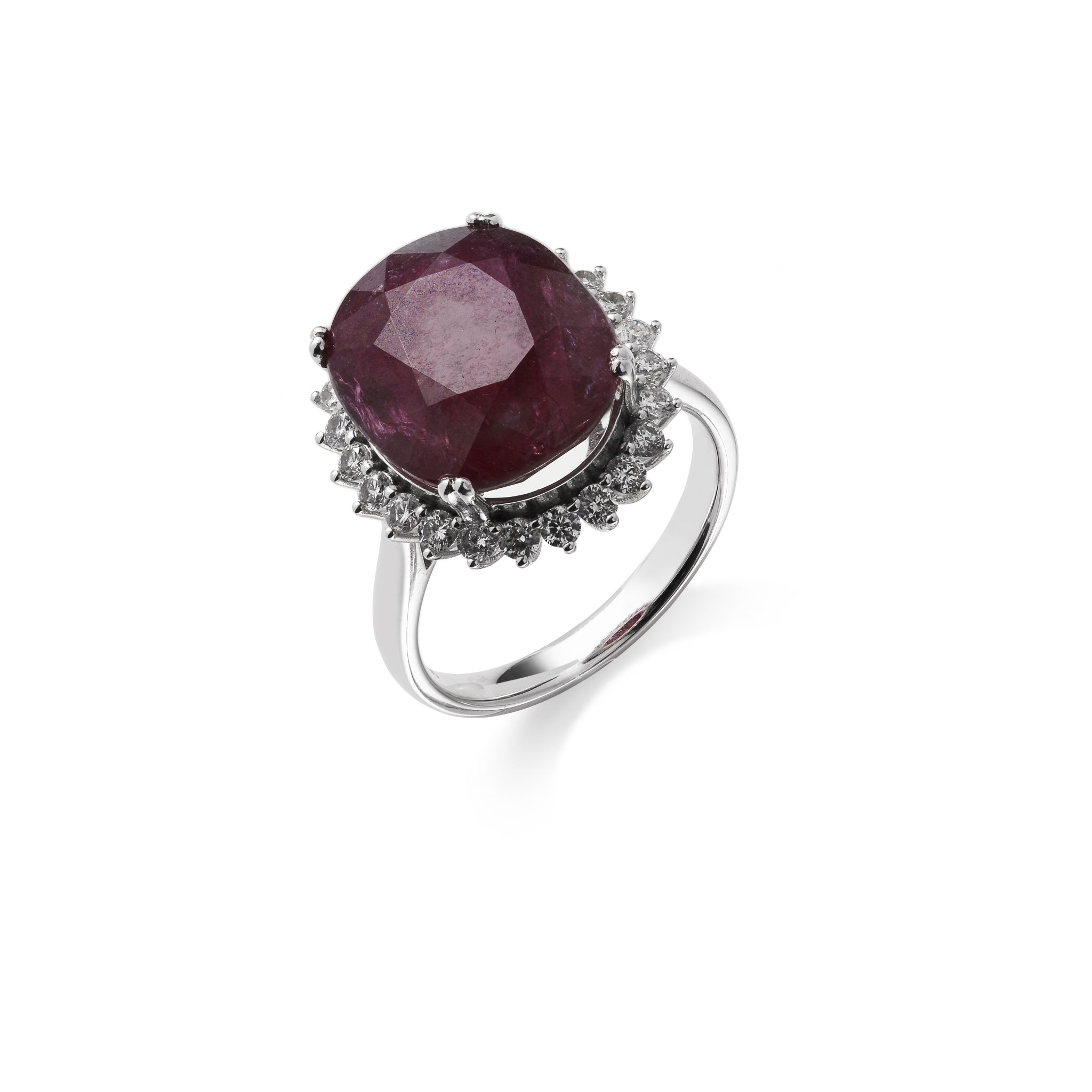 A ruby and diamond cluster ring The oval-cut ruby, weighing 11.87 carats, within a brilliant-cut