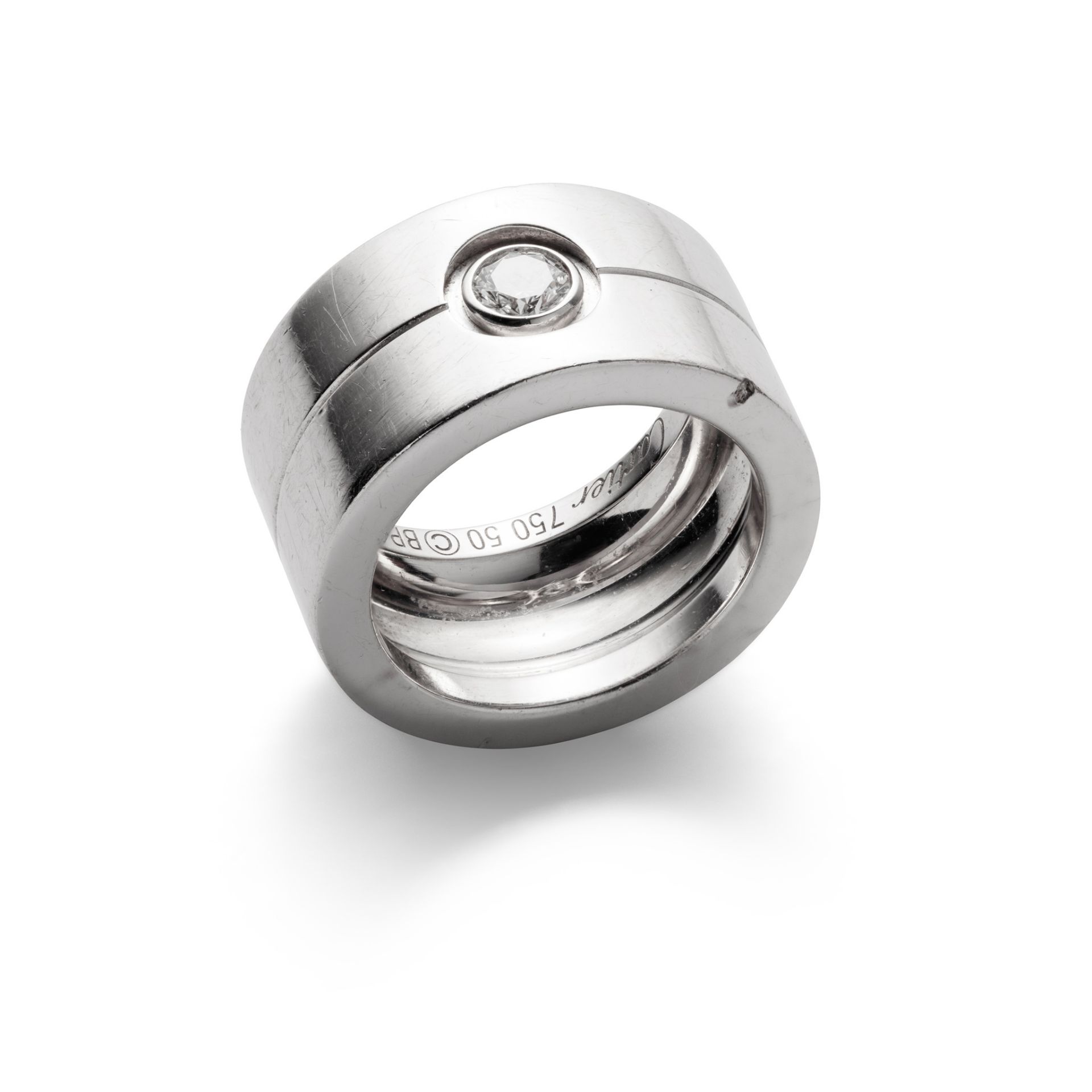 A diamond-set ring, by Cartier The wide 18ct white gold band with engraved central line, collet-