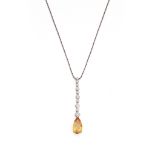 A topaz and diamond pendant The pear-shaped orange topaz, suspended from a graduated line of