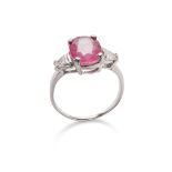 A ruby and diamond ring The oval-cut ruby in a four-claw mount, between triangular-cut diamond