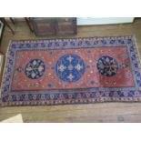 A Turkestan style rug, with three circular medallions on a red field, all filled with foliate