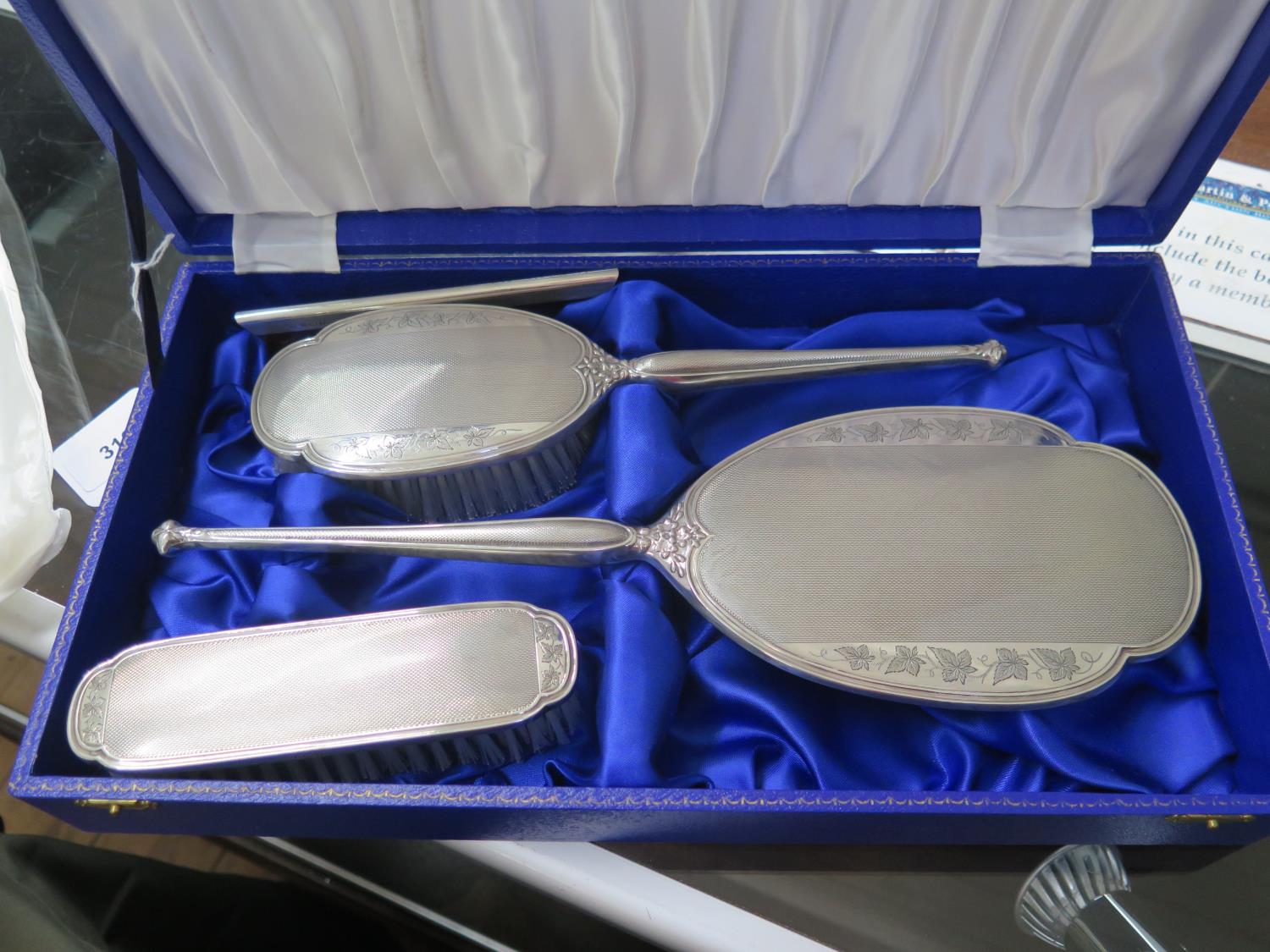 A silver mounted four piece dressing table set, with engine turned and leaf design, in a fitted