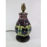 A Moorcroft violets pattern table lamp, with purple flowers on a green ground, 22 cm high