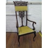 An Edwardian Art Nouveau style armchair, the fret carved high back over a padded seat on cabriole