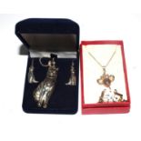 A silver cat pendant necklace with matching cat earrings together with an articulated mouse