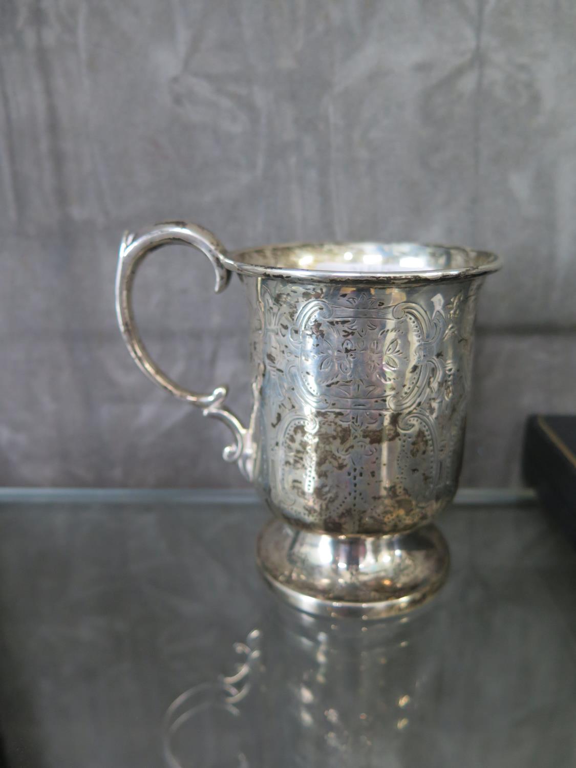 A silver christening mug with bright cut decoration