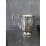 A silver christening mug with bright cut decoration