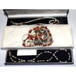 A bag with six pearl, coral and garnet decorated necklaces in boxes