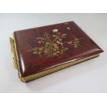 A Japanese red lacquered and mother of pearl inset photo album, containing fifty coloured