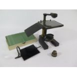 A brass and metal dissecting microscope, with glass top platform and accessories, 19 cm high