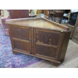 A oak corner side cabinet, with a pair of panelled doors on bracket feet, 123 cm wide, 60 cm deep,