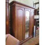 An Edwardian inlaid mahogany two door wardrobe, the doors with oval bevelled mirrors, above two