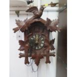 A carved softwood Swiss cuckoo clock, the twin train movement with bellows and coil gong, retail