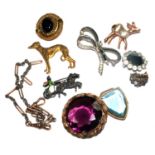 A bag of brooches including one with a large purple stone