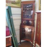 An Edwardian mahogany and satinwood crossbanded corner cabinet, the glazed door enclosing velvet